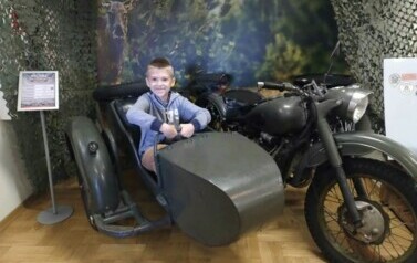 Chłopiec pozuje do zdjęcia w zabytkowym motocyklu.