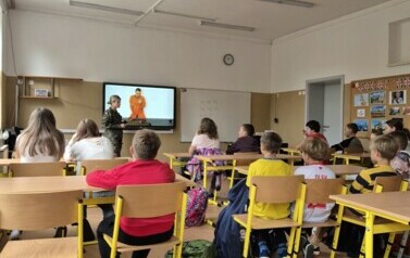 Uczniowie w sali lekcyjnej oglądają prezentację multimedialną dotyczącą udzielania pierwszej pomocy.