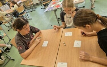 Trzy dziewczynki z klasy piątek grają w bingo z tabliczką mnożenia.