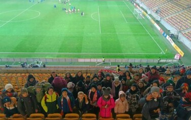 Grupa uczni&oacute;w stojąca na tle Stadionu Miejskiego w Białymstoku.