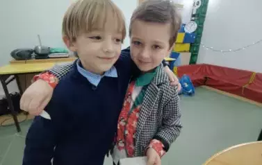 Dw&oacute;ch chłopc&oacute;w z klasy pierwszej dzieli się opłatkiem