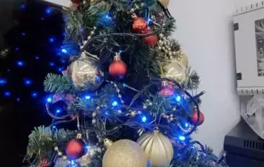 Choinka ozdobiona złotymi bombkami i niebieskimi lampkami