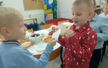 Dw&oacute;ch chłopc&oacute;w z klasy pierwszej dzieli się opłatkiem