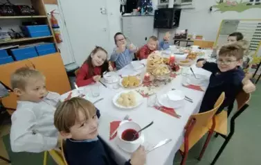 Uczniowie klasy pierwszej pozują do zdjęcia przy świątecznym stole