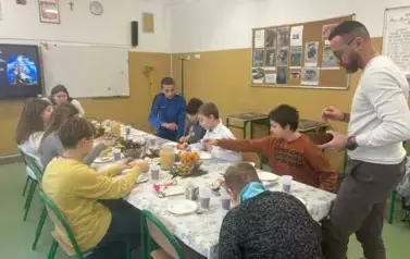 Uczniowie klasy sz&oacute;stej z nauczycielem przy wigilijnym stole