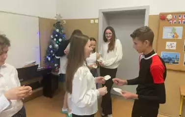 Uczeń klasy si&oacute;dmej dzieli się opłatkiem i składa życzenia świąteczne koleżance z klasy