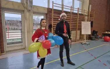 Osoby prowadzące Bitwę Mikołajkową w strojach mikołajkowych i z kolorowymi balonami