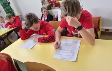 Dw&oacute;ch chłopc&oacute;w siedzi w ławce szkolnej