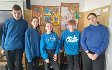 Uczniowie klasy &oacute;smej w czarnych spodniach i niebieskich bluzach
