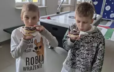 Dw&oacute;ch chłopc&oacute;w z klasy pierwszej z pączkami