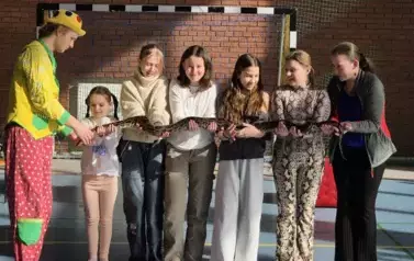 Dziewczynki stoją obok siebie i na wyciągniętych dłoniach trzymają węża