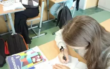Uczennice siedzące w ławce wykonujące kodowanie