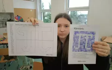 Uczennica trzymająca w rękach prace swojej grupy
