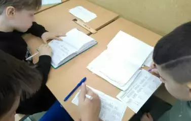 Uczniowie siedzący w ławce i rozwiązujący szyfrowankę