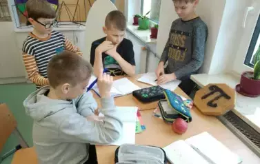 Uczniowie przy ławce wykonujący zadanie