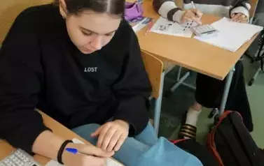 Uczeń ze swoim zadaniem siedzący w ławce