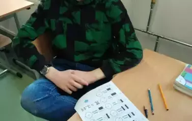 Uczeń z zadaniem siedzący w ławce