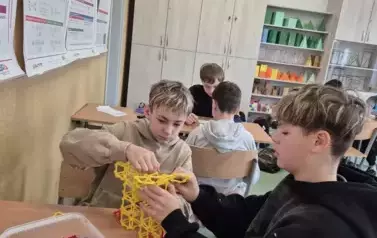 Dw&oacute;ch chłopc&oacute;w buduję bryłę liczby Pi z klock&oacute;w reko