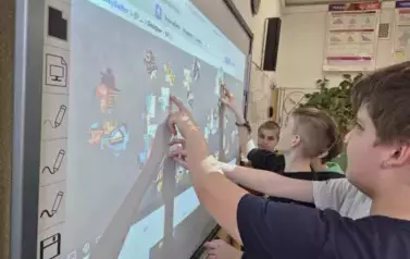 Chłopcy ukłądają puzzle na tablicy multimedialnej
