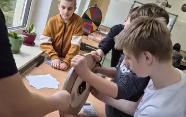 Chłopcy mierzą obw&oacute;d drewnianego koła