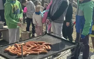Dzieci pieką kiełbaski na ognisku