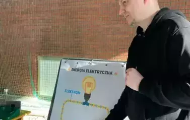 Mężczyzna wskazuje na rysunek baterii i zar&oacute;wki