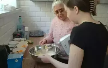Uczennica z panią z domu Dziennego przygotowująca ciasto na gofry