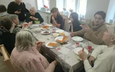 Uczennice z osobami z Domu Dziennego siedzące przy stole