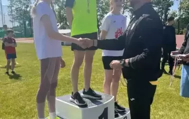 Trener składa gratulacje dziewczynce, kt&oacute;ra zajęła II miejsce w zawodach sportowych