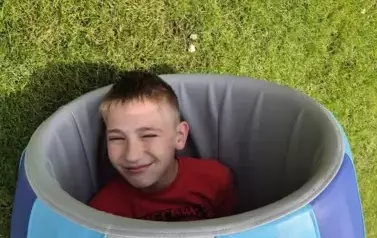 Chłopiec w piankowej beczce na trawie