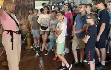 Uczniowie stoją i słuchają wykładu pani przewodnik
