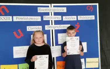 Zwycięzcy w konkursie pozują z dyplomamina tle niebieskiej tablicy