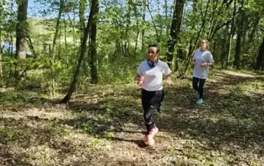 Dwie kobiety w sportowych strojach biegną przez las