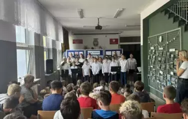 Grupa uczni&oacute;w ubranych w str&oacute;j galowy występuje podczas akademii