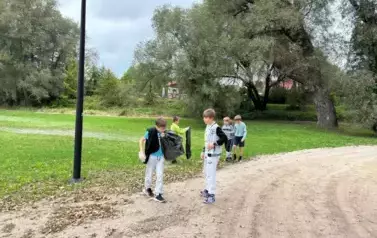 Chłopcy trzymają worki i sprzątaja teren