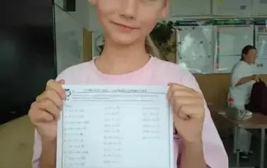 Uczennica pokazuje kartkę z wykonaną pracą