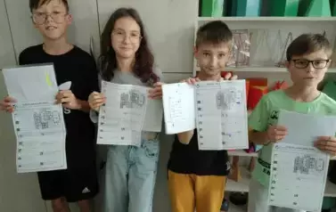 Uczniowie stoją przy szafie i prezentują wykonane prace