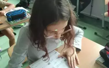 Uczniowie siedzą w ławkach i wykonują karty pracy