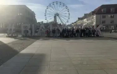 Uczestnicy wycieczki pozują do zdjęcia na tle napisu Białystok