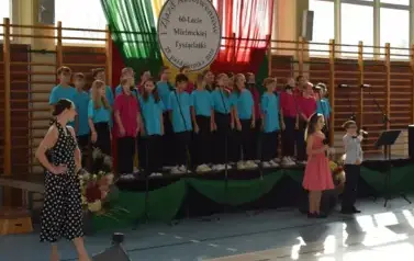 Grupa uczni&oacute;w ubranych na koorowo śpiewa i tańczy