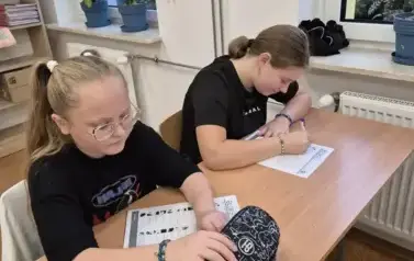 Uczennice z klasy piątej rozwiązują zadania matematyczne