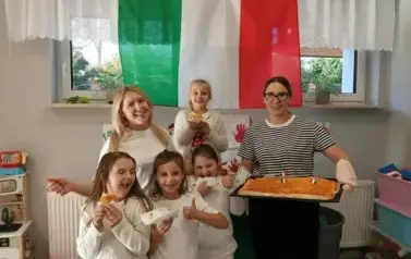 Uczniowie wraz z nauczycielkami trzymaja pizzę