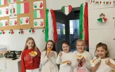 Uczennice na tle barw flagi włoskiej jedza pizzę