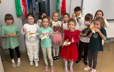 Ucznieowie i uczennice pozują do zdjęcia z pizzą w ręku