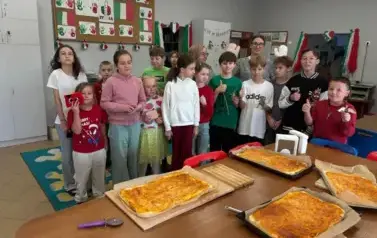Grupa uczni&oacute;w, ktorzy przygotowywali pizzę pozuje do zdjęcia