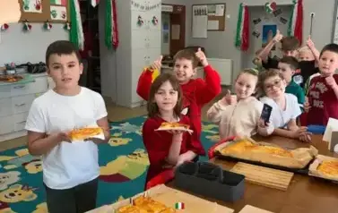 Grupa uczni&oacute;w z pizzą pozuje do zdjęcia