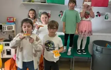 Grupa uczni&oacute;w trzym pizzę w ręku