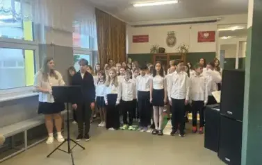 Uczniowie ubrani w w stroje galowe występują podczas akademii