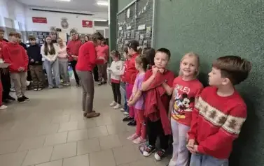 Dzieci w czerwonych strojach czekają na odbi&oacute;r nagr&oacute;d za udział w konkursie plastycznym Dzieciństwo bez przemocy