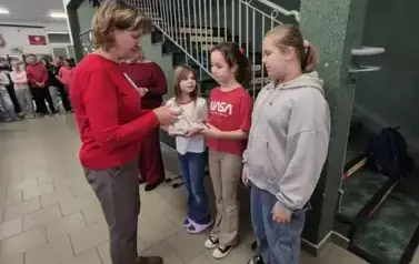 Trzy dziewczynki otrzymują nagrody za udział w konursie literackim